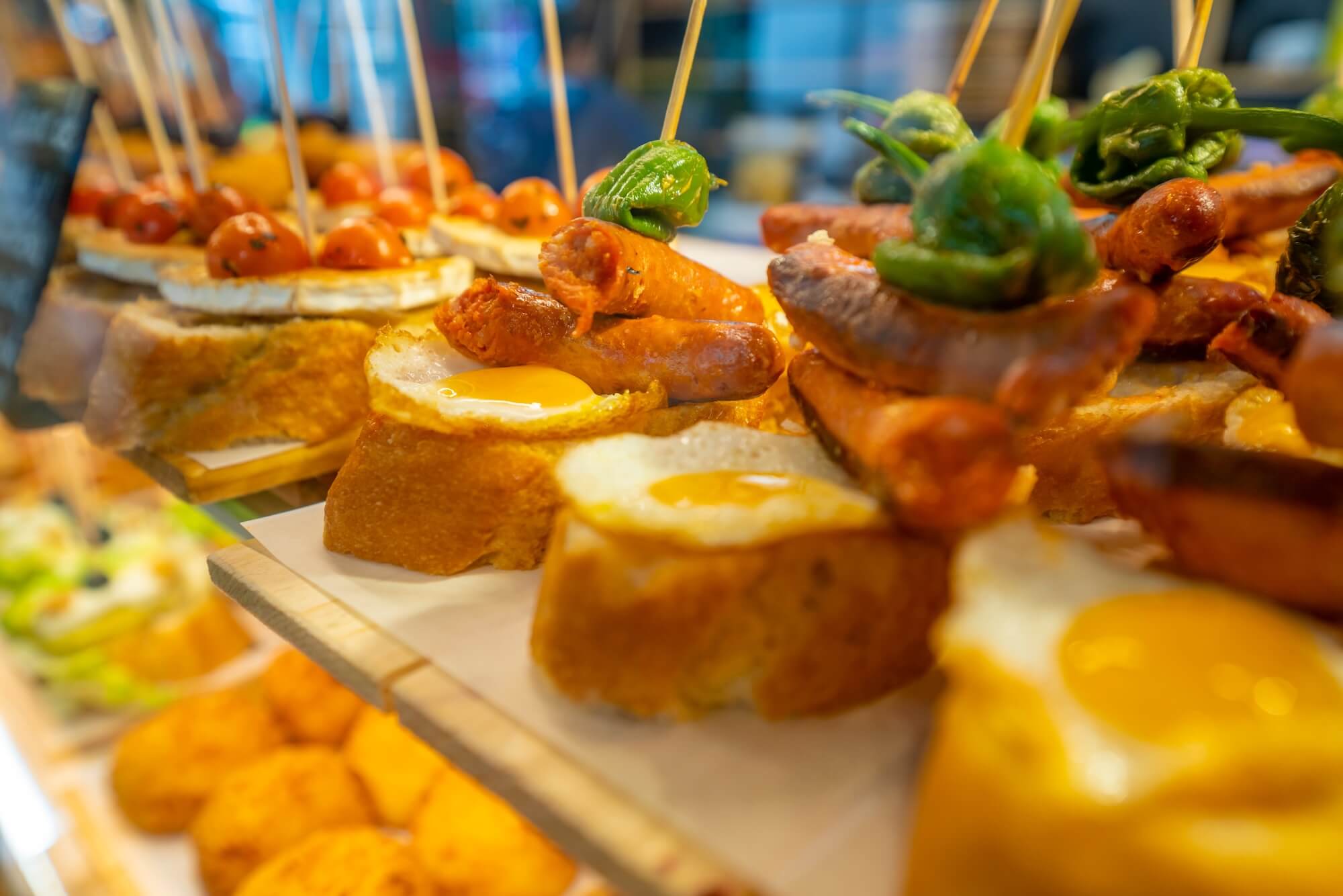 Close-up of traditional Spanish tapas with fried eggs, sausages, and peppers served on crusty bread, representing Supr Bueno’s custom Shopify web design services for tapas bars, restaurants, and local food shops in Spain.